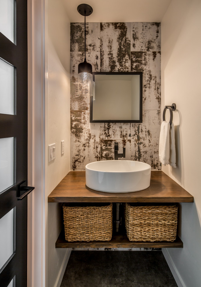 Modern inredning av ett litet badrum, med skåp i mellenmörkt trä, svart och vit kakel, keramikplattor, vita väggar, klinkergolv i keramik, ett fristående handfat, träbänkskiva och svart golv