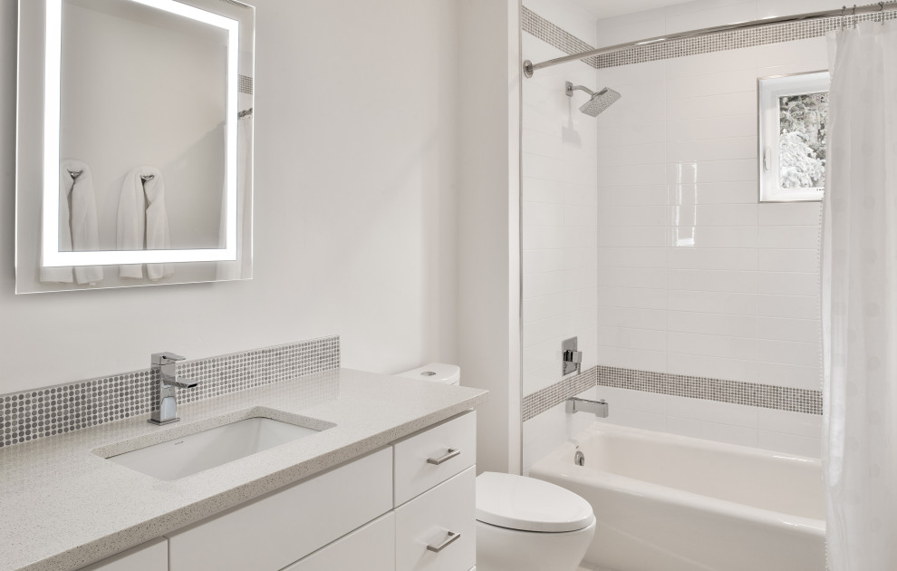 Стильный дизайн: ванная комната среднего размера в современном стиле с плоскими фасадами, белыми фасадами, душем над ванной, раздельным унитазом, белой плиткой, керамогранитной плиткой, белыми стенами, полом из керамогранита, врезной раковиной, столешницей из искусственного кварца, белым полом, шторкой для ванной, серой столешницей, тумбой под одну раковину и встроенной тумбой - последний тренд