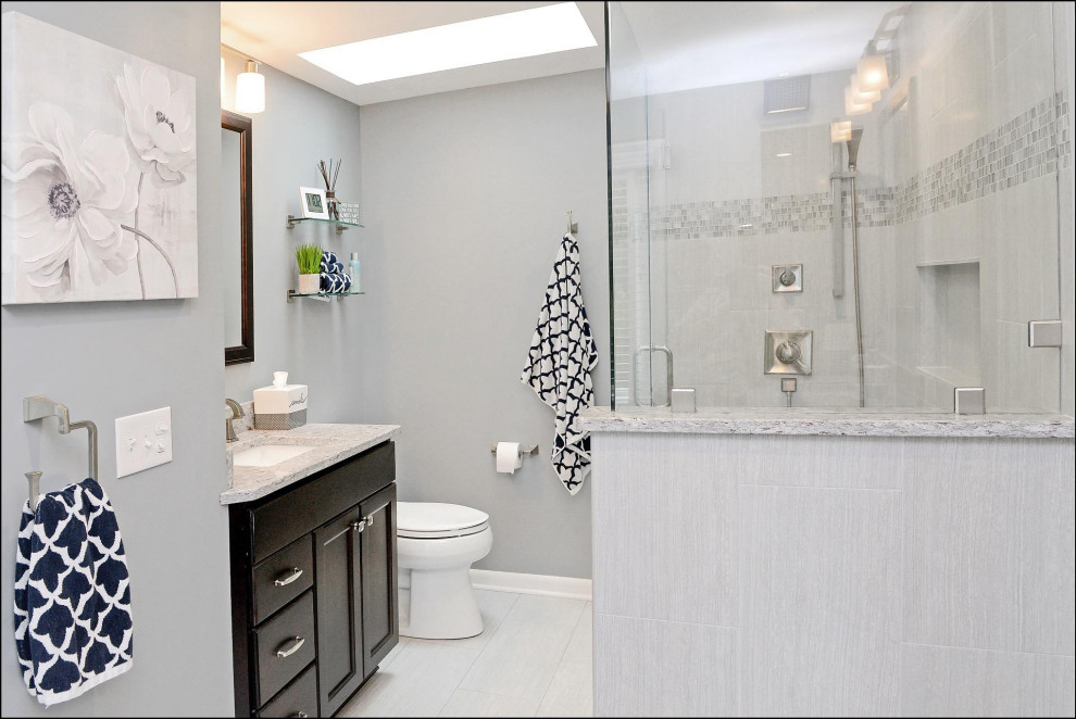 Inspiration for a medium sized traditional shower room bathroom in New York with recessed-panel cabinets, dark wood cabinets, a two-piece toilet, grey tiles, ceramic tiles, grey walls, laminate floors, a built-in sink, granite worktops, grey floors, a hinged door, grey worktops, a single sink and a built in vanity unit.