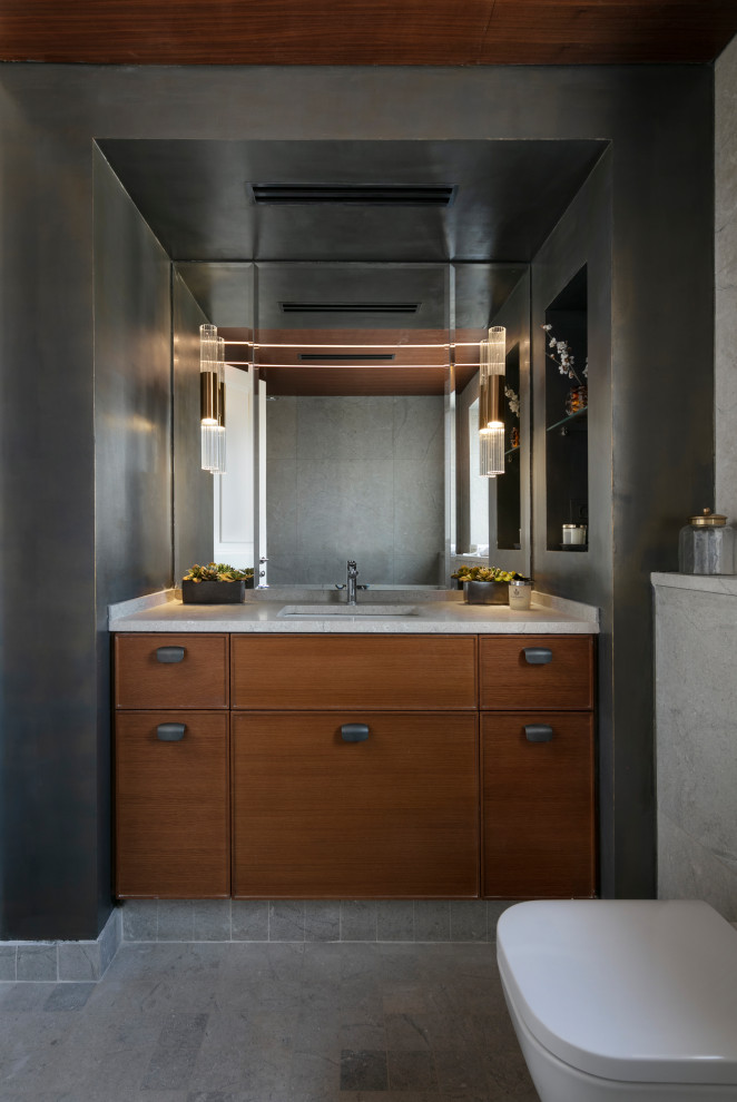 Example of a mid-sized trendy master gray tile marble floor, gray floor, single-sink, wood ceiling and wall paneling bathroom design in Other with raised-panel cabinets, medium tone wood cabinets, a wall-mount toilet, gray walls, an undermount sink, marble countertops, gray countertops, a niche and a built-in vanity