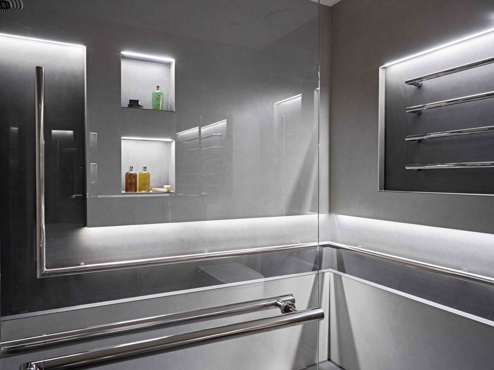 Cette image montre une salle d'eau minimaliste de taille moyenne avec une douche ouverte, WC suspendus, un carrelage gris, des carreaux de porcelaine, un mur gris, un sol en carrelage de porcelaine, un lavabo suspendu et un sol gris.