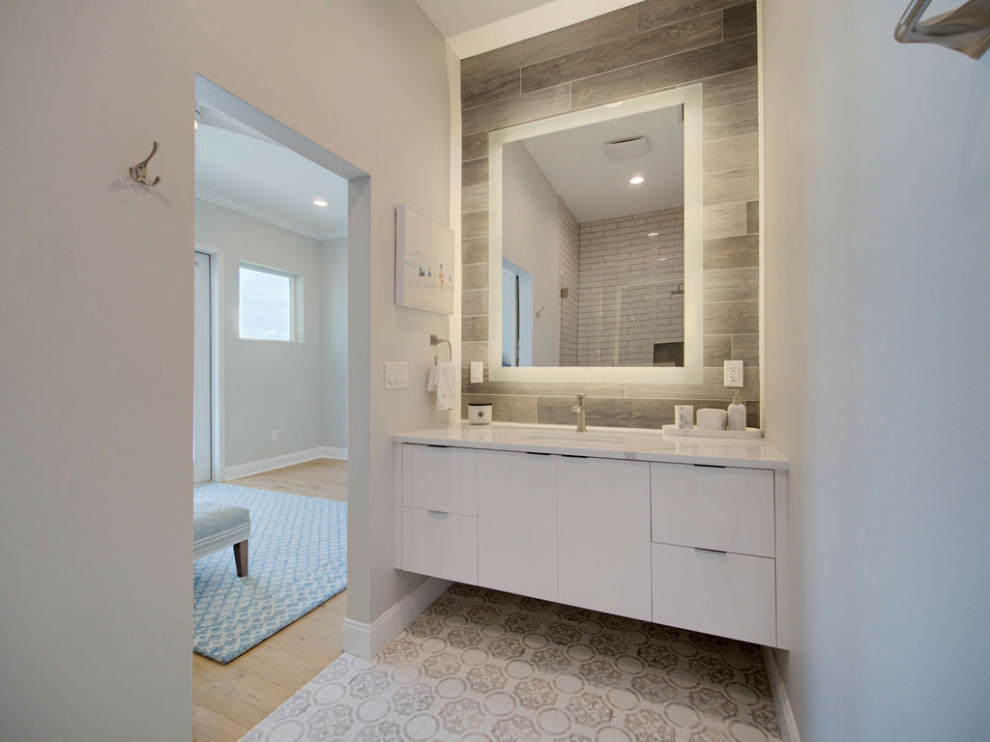 Example of a mid-sized beach style master gray tile and porcelain tile mosaic tile floor, multicolored floor and single-sink alcove shower design in Tampa with flat-panel cabinets, white cabinets, gray walls, an undermount sink, quartzite countertops, a hinged shower door, white countertops and a floating vanity