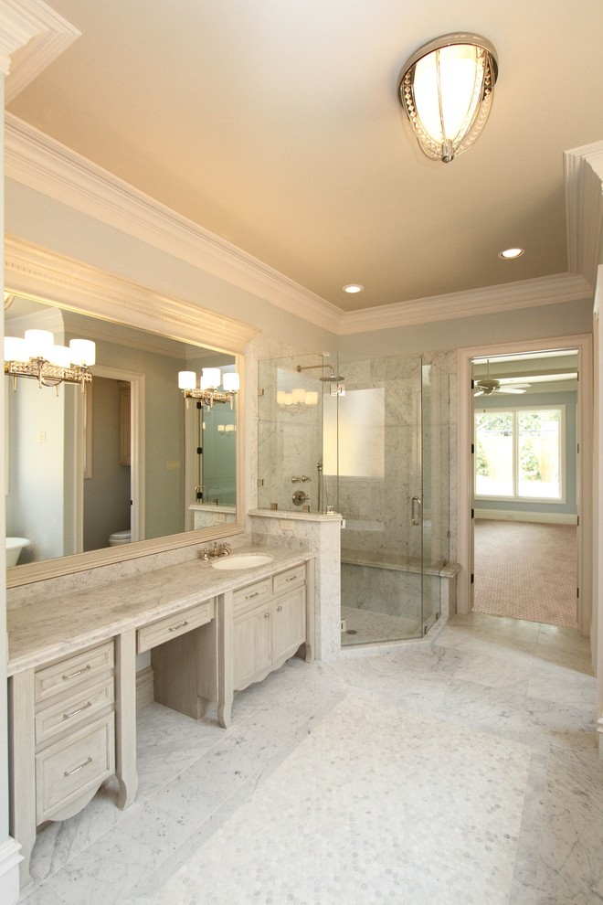 Klassisk inredning av ett stort en-suite badrum, med luckor med infälld panel, beige skåp, ett badkar med tassar, en hörndusch, stenkakel, marmorgolv, ett undermonterad handfat och marmorbänkskiva