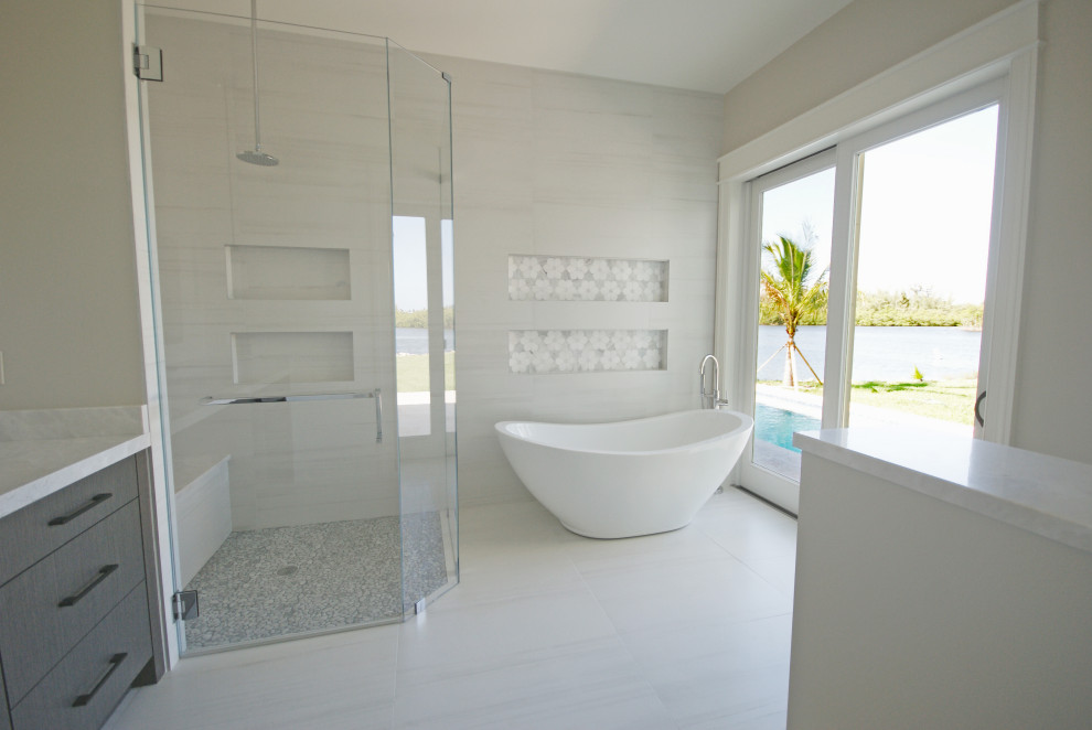 Medium sized world-inspired ensuite bathroom in Miami with flat-panel cabinets, grey cabinets, a freestanding bath, a corner shower, a one-piece toilet, grey tiles, ceramic tiles, grey walls, ceramic flooring, a submerged sink, quartz worktops, grey floors, a hinged door and grey worktops.