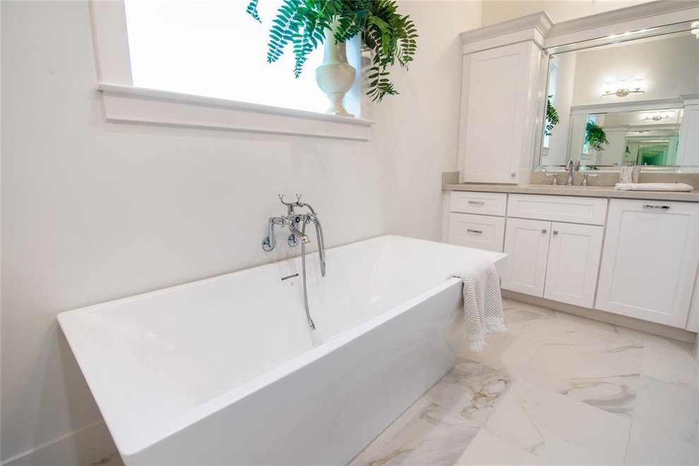 На фото: большая главная ванная комната в современном стиле с фасадами в стиле шейкер, белыми фасадами, отдельно стоящей ванной, душем над ванной, унитазом-моноблоком, белой плиткой, керамогранитной плиткой, белыми стенами, полом из керамогранита, врезной раковиной, столешницей из искусственного кварца, белым полом, душем с распашными дверями и белой столешницей с