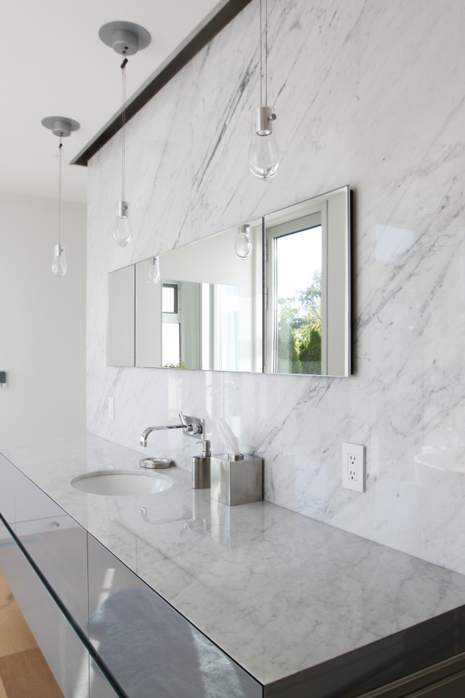 Inspiration för små moderna vitt en-suite badrum, med släta luckor, grå skåp, ett fristående badkar, en kantlös dusch, en vägghängd toalettstol, vit kakel, marmorkakel, vita väggar, mellanmörkt trägolv, ett undermonterad handfat, marmorbänkskiva och dusch med gångjärnsdörr