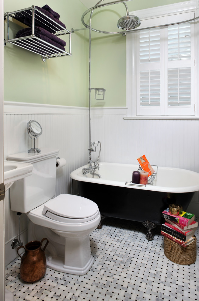 На фото: ванная комната в классическом стиле с ванной на ножках и зелеными стенами