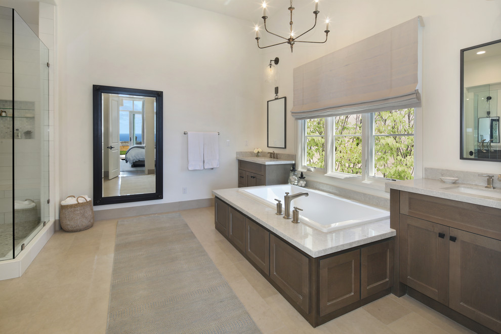 This is an example of an expansive mediterranean ensuite bathroom in Orange County with shaker cabinets, medium wood cabinets, a corner shower, ceramic tiles, white walls, limestone flooring, a wall-mounted sink, engineered stone worktops, grey floors, a hinged door and beige worktops.
