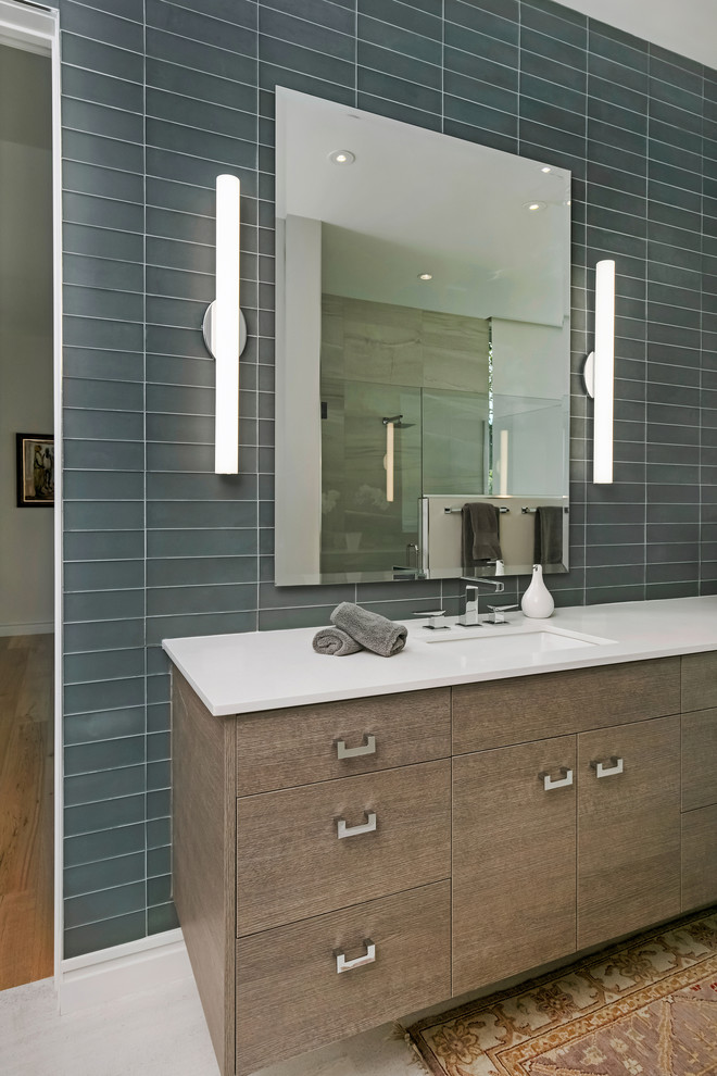 This is an example of a large contemporary ensuite bathroom in Tampa with flat-panel cabinets, brown cabinets, a freestanding bath, a built-in shower, a two-piece toilet, grey tiles, glass tiles, white walls, porcelain flooring, a submerged sink, engineered stone worktops, grey floors, a hinged door and white worktops.