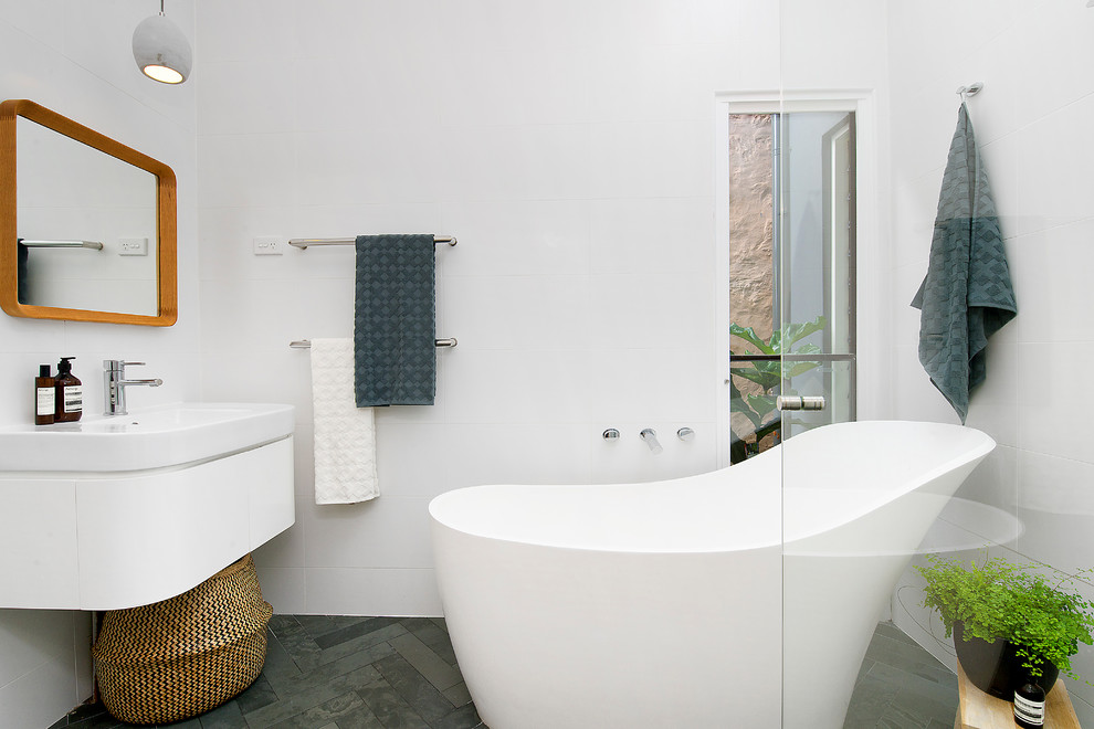 Идея дизайна: главная ванная комната в современном стиле с белыми фасадами, отдельно стоящей ванной, белой плиткой, полом из сланца, серым полом, плоскими фасадами, монолитной раковиной, керамической плиткой, белыми стенами и белой столешницей