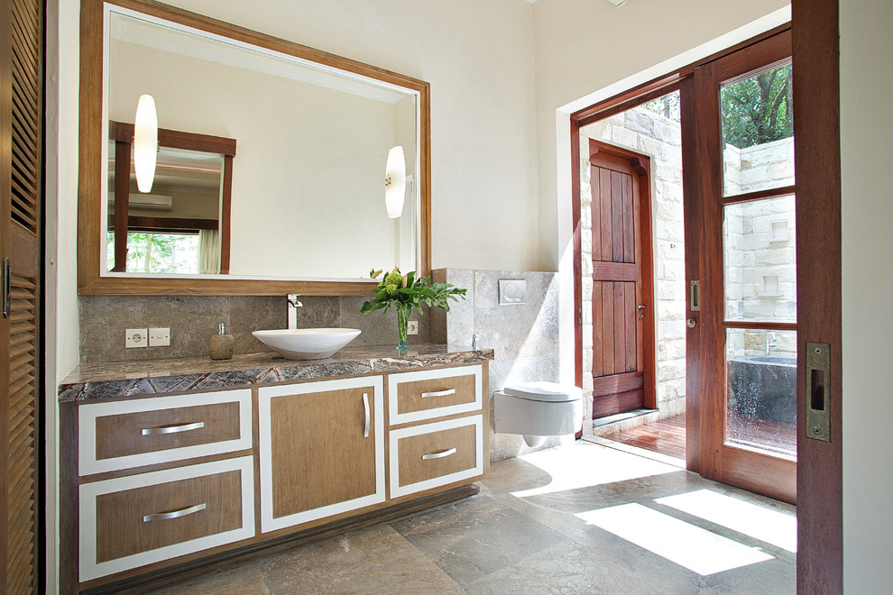 Cette photo montre une salle de bain asiatique en bois brun avec une vasque, un placard à porte plane, un carrelage gris, un mur blanc et un mur en pierre.