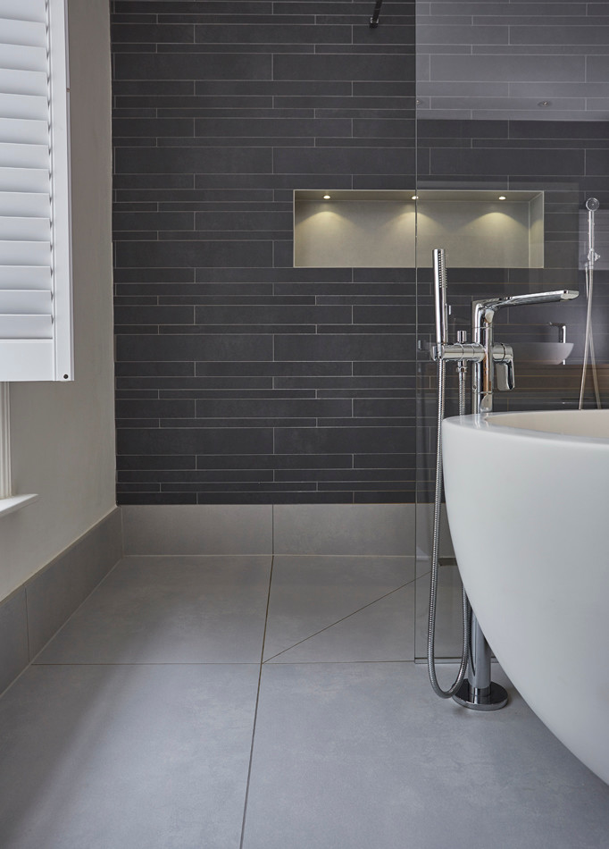 Photo of a large contemporary ensuite bathroom in Devon with light wood cabinets, a freestanding bath, a double shower, a wall mounted toilet, grey tiles, porcelain tiles, white walls, porcelain flooring, a wall-mounted sink and wooden worktops.