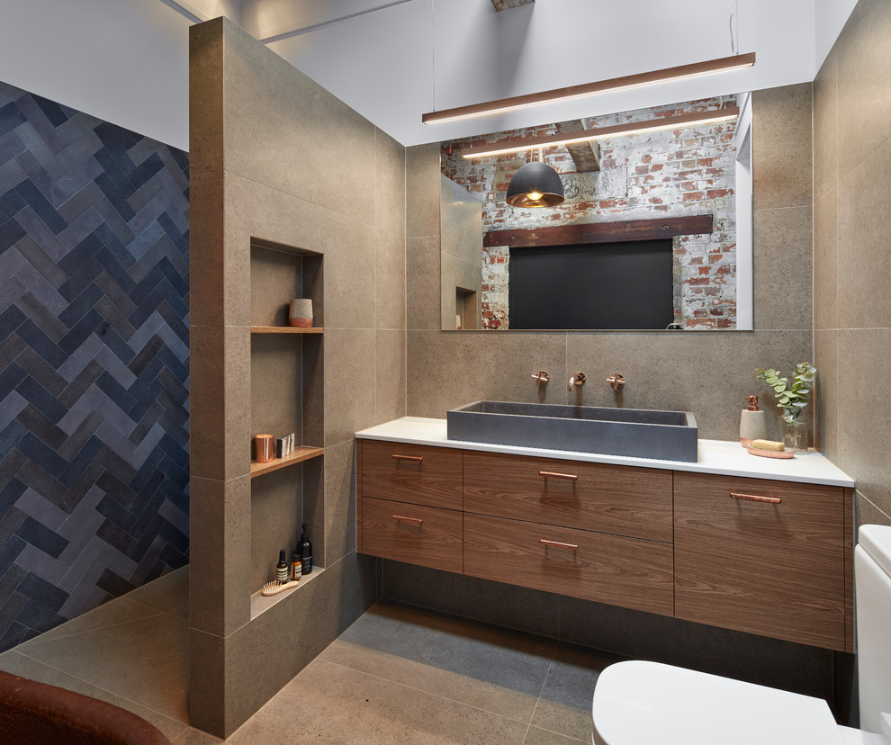 Photo of a large industrial ensuite bathroom in Melbourne with flat-panel cabinets, dark wood cabinets, a freestanding bath, an alcove shower, a one-piece toilet, grey tiles, porcelain tiles, white walls, porcelain flooring, a vessel sink, engineered stone worktops, grey floors and an open shower.