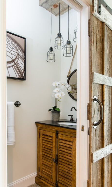 Cette image montre une petite salle de bain urbaine en bois clair avec un placard à porte persienne, un mur gris, un sol en vinyl et un plan de toilette en granite.