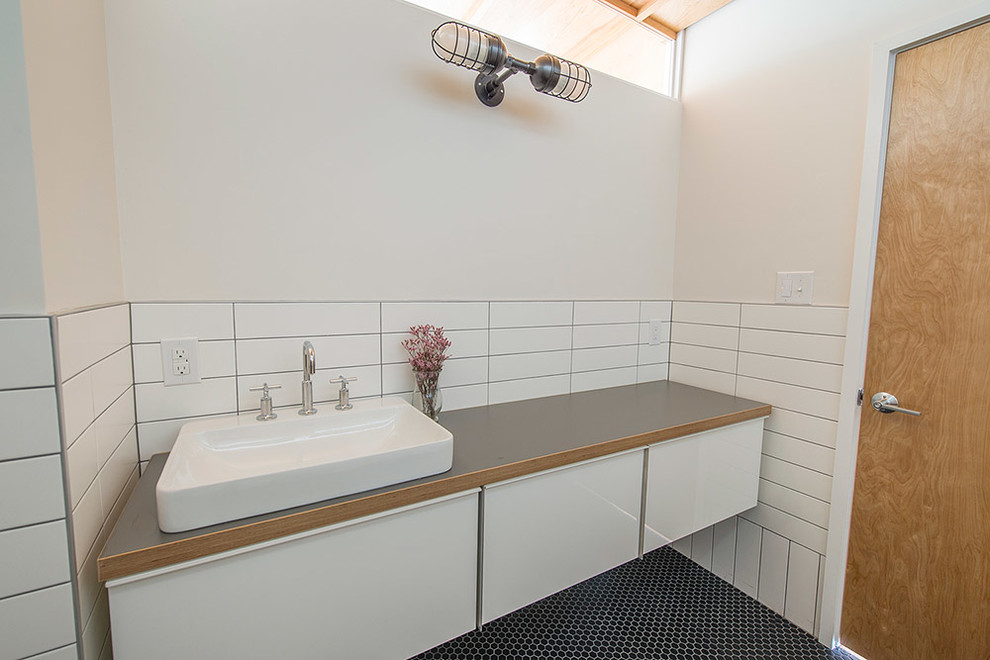 Идея дизайна: ванная комната в стиле лофт с накладной раковиной, плоскими фасадами, белыми фасадами, столешницей из ламината, ванной в нише, душем над ванной, раздельным унитазом, черной плиткой, керамической плиткой, белыми стенами и полом из керамической плитки