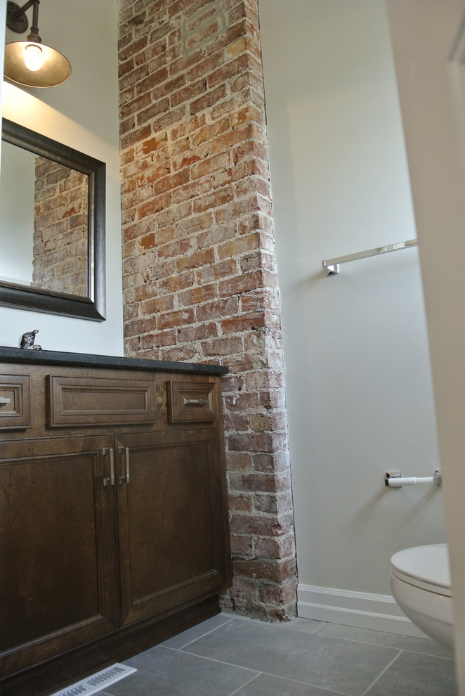 Immagine di una piccola stanza da bagno con doccia industriale con lavabo sottopiano, ante in stile shaker, ante in legno bruno, top in granito, piastrelle grigie, piastrelle in gres porcellanato, pareti grigie e pavimento in gres porcellanato