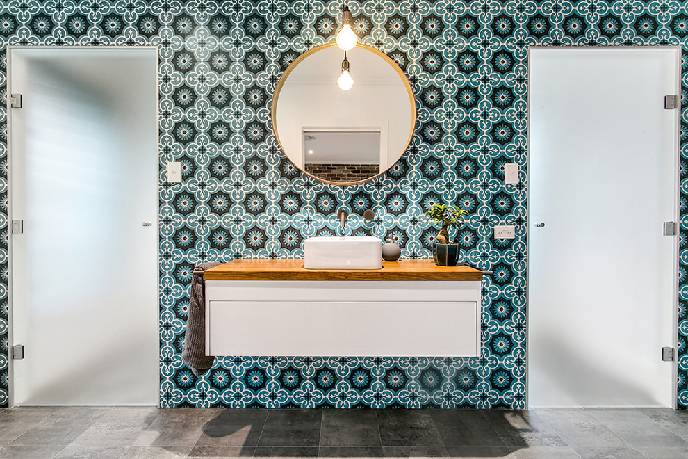 Inspiration for a contemporary multicolored tile and cement tile gray floor bathroom remodel in Other with flat-panel cabinets, white cabinets, a vessel sink, wood countertops, a hinged shower door and brown countertops