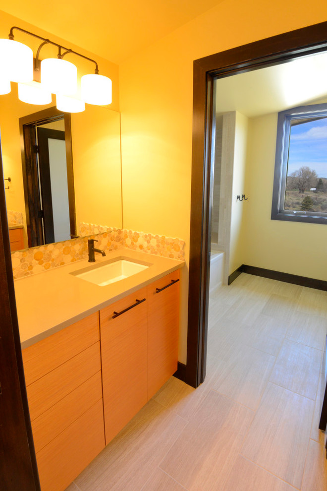 Photo of a large classic ensuite bathroom in Orange County with flat-panel cabinets, light wood cabinets, brown tiles, mosaic tiles, yellow walls, porcelain flooring, a submerged sink, solid surface worktops and beige floors.
