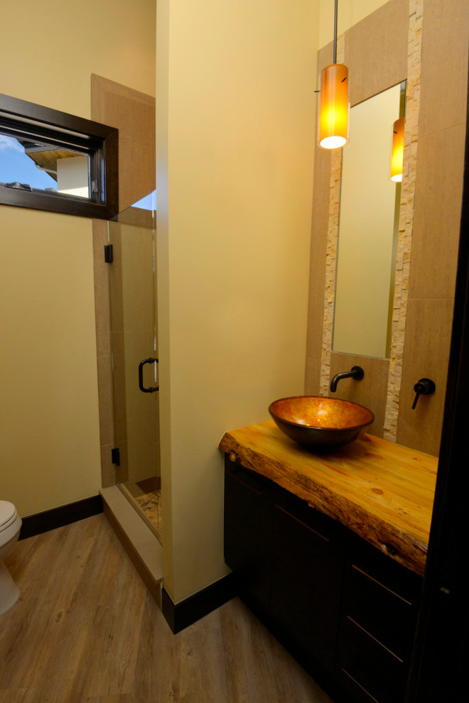 Bild på ett mellanstort rustikt badrum med dusch, med släta luckor, skåp i mörkt trä, en dusch i en alkov, gula väggar, vinylgolv, ett fristående handfat, träbänkskiva och brunt golv