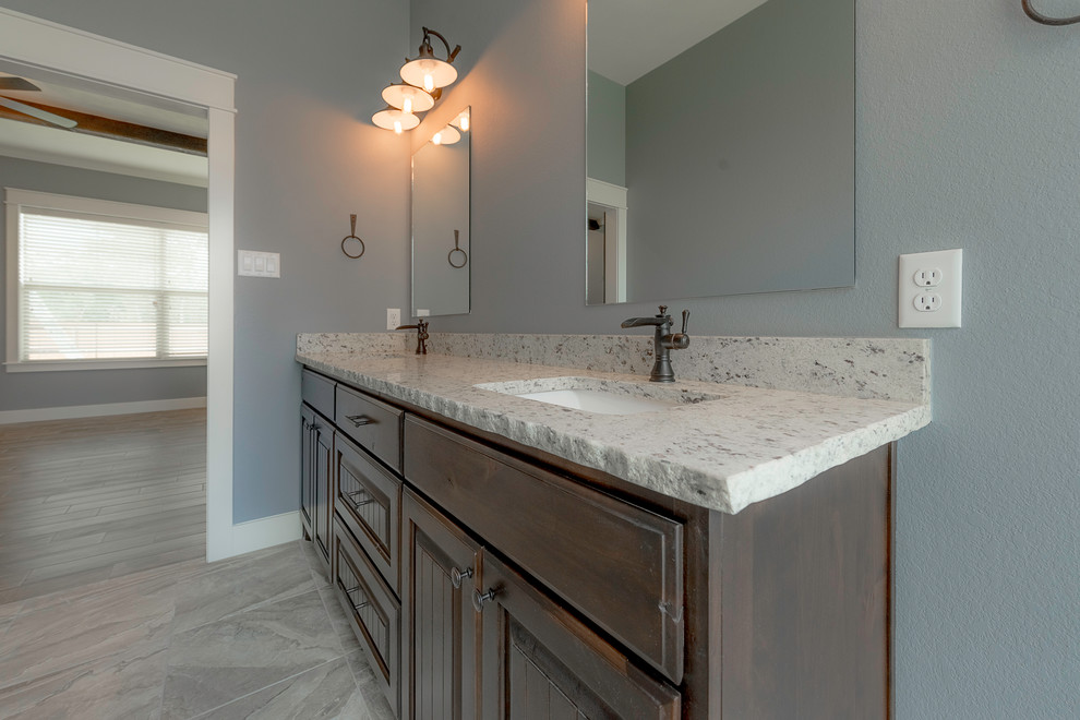 Example of a mid-sized country master gray tile and ceramic tile ceramic tile and multicolored floor bathroom design in Other with raised-panel cabinets, dark wood cabinets, a two-piece toilet, gray walls, an undermount sink, granite countertops and a hinged shower door