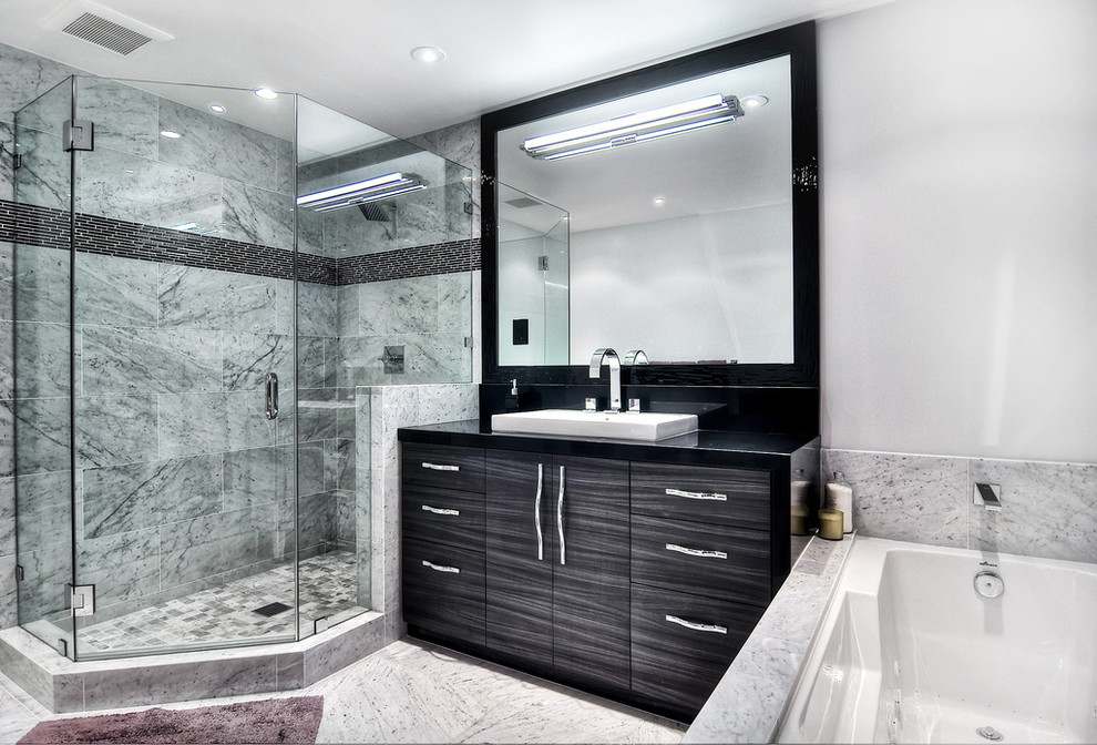 Inredning av ett modernt mellanstort en-suite badrum, med släta luckor, svarta skåp, ett hörnbadkar, en dusch i en alkov, en toalettstol med hel cisternkåpa, grå kakel, stenkakel, vita väggar, betonggolv, ett fristående handfat och granitbänkskiva