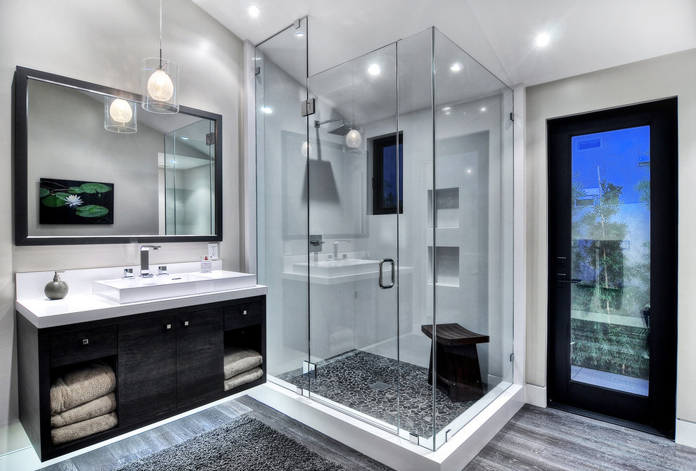 Inspiration for a medium sized contemporary grey and white ensuite bathroom in Orange County with a vessel sink, flat-panel cabinets, black cabinets, an alcove shower, a corner bath, a one-piece toilet, grey tiles, stone tiles, white walls, concrete flooring, granite worktops, grey floors and a hinged door.