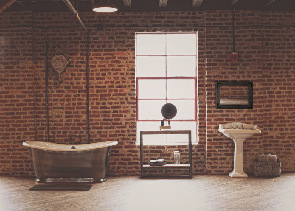На фото: ванная комната в стиле лофт с отдельно стоящей ванной и раковиной с пьедесталом
