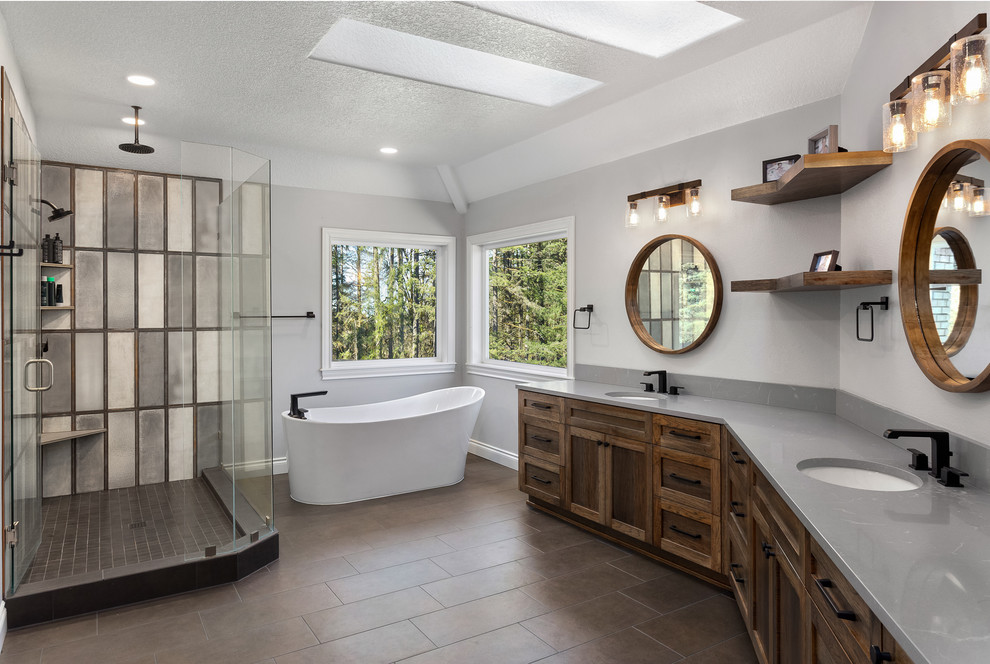 Bild på ett stort industriellt grå grått en-suite badrum, med skåp i shakerstil, skåp i mörkt trä, ett fristående badkar, en hörndusch, grå kakel, grå väggar, ett undermonterad handfat, brunt golv och dusch med gångjärnsdörr