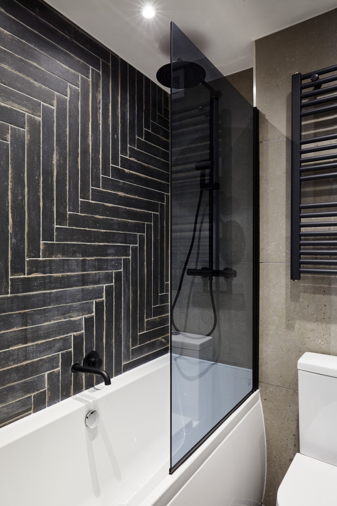 Exempel på ett industriellt badrum, med ett badkar i en alkov, en dusch/badkar-kombination, en toalettstol med hel cisternkåpa, svart kakel, grå väggar och med dusch som är öppen
