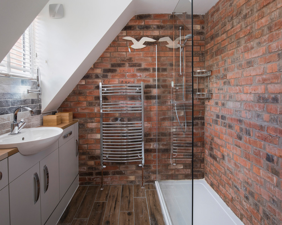 Industriell inredning av ett litet brun brunt badrum med dusch, med släta luckor, vita skåp, en hörndusch, röda väggar, ett integrerad handfat, träbänkskiva och brunt golv