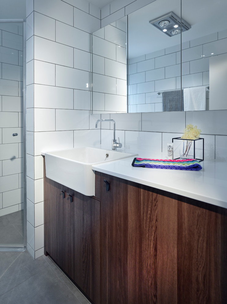 Small contemporary shower room bathroom in Other with dark wood cabinets, a corner shower, a two-piece toilet, white tiles, ceramic tiles, white walls, ceramic flooring, solid surface worktops, flat-panel cabinets, a built-in sink, grey floors, a hinged door and white worktops.