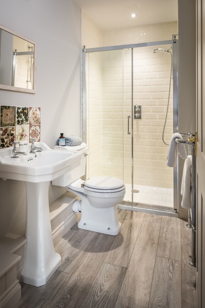 Inredning av ett maritimt mellanstort en-suite badrum, med en öppen dusch, en toalettstol med separat cisternkåpa, gul kakel, keramikplattor, vita väggar, ljust trägolv, ett piedestal handfat, grått golv och dusch med skjutdörr
