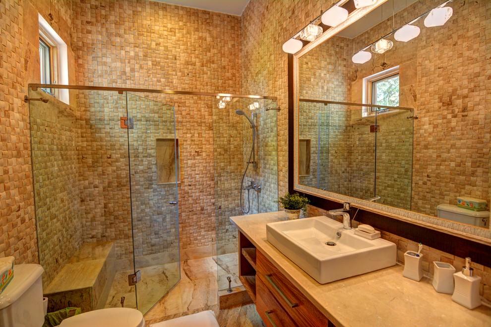 Immagine di una grande stanza da bagno per bambini tropicale con lavabo rettangolare, ante di vetro, ante in legno chiaro, top in marmo, vasca freestanding, WC a due pezzi, piastrelle beige, piastrelle a mosaico e pavimento in travertino