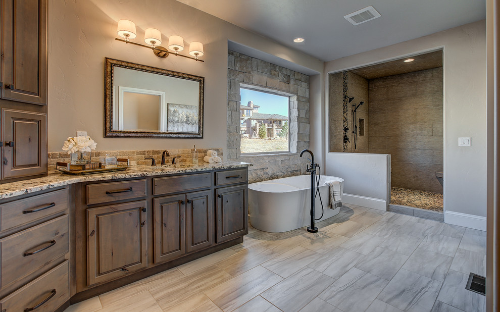 Bild på ett mellanstort vintage en-suite badrum, med luckor med upphöjd panel, skåp i mellenmörkt trä, en dusch i en alkov, beige kakel, porslinskakel, beige väggar, travertin golv, ett undermonterad handfat, granitbänkskiva och ett fristående badkar