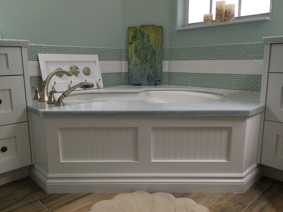 Пример оригинального дизайна: главная ванная комната среднего размера в морском стиле с фасадами с филенкой типа жалюзи, белыми фасадами, угловой ванной, синей плиткой, зеленой плиткой, плиткой мозаикой, зелеными стенами, полом из керамогранита, врезной раковиной, мраморной столешницей и коричневым полом