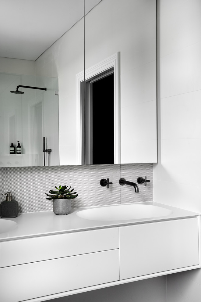Inredning av ett modernt mellanstort vit vitt badrum, med vita skåp, vit kakel, porslinskakel, vita väggar, klinkergolv i porslin, ett undermonterad handfat, bänkskiva i akrylsten och grått golv
