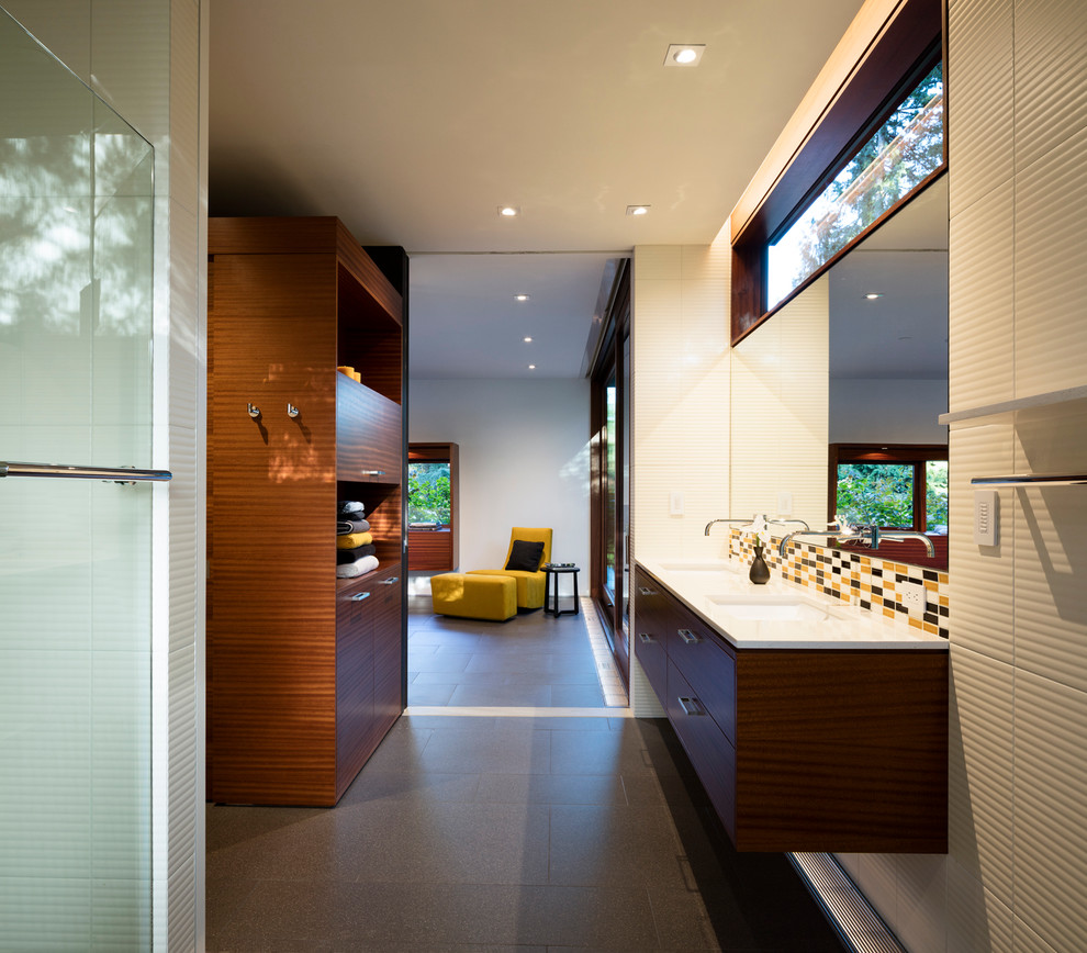 Exemple d'une salle de bain principale moderne en bois brun avec un placard à porte plane, une baignoire indépendante, une douche à l'italienne, un carrelage noir, des carreaux de porcelaine, un mur blanc, un lavabo encastré et un plan de toilette en surface solide.