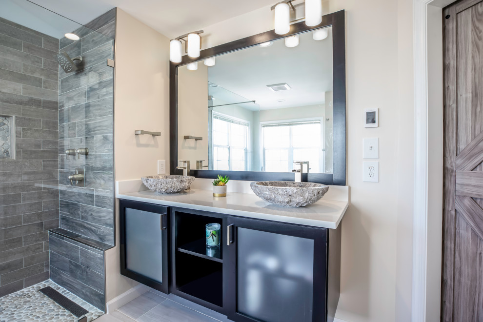 This is an example of a medium sized classic ensuite bathroom in DC Metro with black cabinets, a freestanding bath, a two-piece toilet, grey tiles, grey walls, ceramic flooring, a vessel sink, granite worktops, grey floors, a hinged door and white worktops.