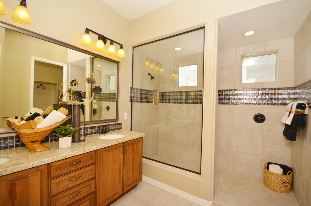 Photo of a medium sized mediterranean ensuite bathroom in Phoenix with a built-in sink, recessed-panel cabinets, medium wood cabinets, engineered stone worktops, a built-in shower, a one-piece toilet, green tiles, glass tiles, beige walls and porcelain flooring.