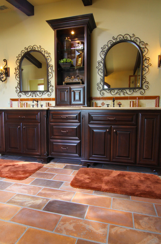 На фото: большая главная ванная комната в средиземноморском стиле с врезной раковиной, фасадами с выступающей филенкой, темными деревянными фасадами, бежевой плиткой, керамической плиткой, бежевыми стенами и полом из терракотовой плитки с