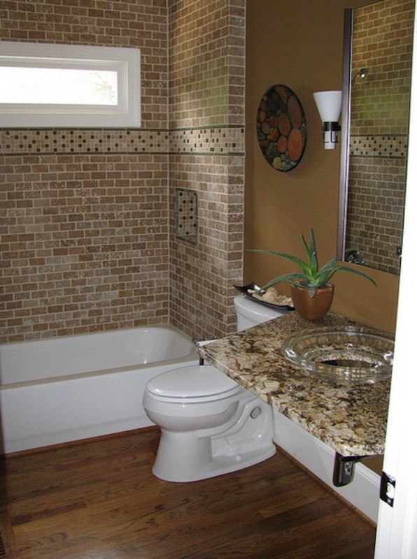 Foto di una stanza da bagno minimal di medie dimensioni con lavabo da incasso, ante in legno bruno, top in granito, vasca ad alcova, WC a due pezzi, piastrelle beige, pareti marroni e pavimento in legno massello medio