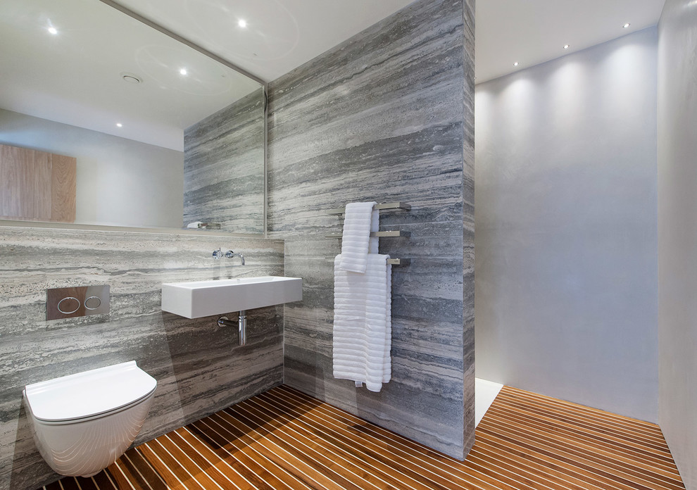 Exempel på ett modernt badrum, med ett väggmonterat handfat, en öppen dusch, en vägghängd toalettstol, grå kakel, grå väggar, mörkt trägolv och med dusch som är öppen