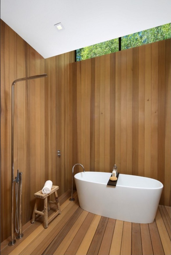 Cette image montre une petite salle de bain design avec une baignoire indépendante, une douche ouverte, un mur marron, parquet foncé, un sol marron et aucune cabine.