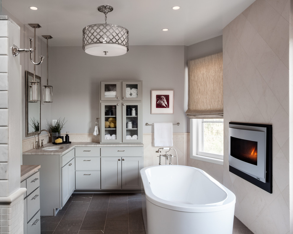 ワシントンD.C.にあるトランジショナルスタイルのおしゃれな浴室 (アンダーカウンター洗面器、シェーカースタイル扉のキャビネット、グレーのキャビネット、置き型浴槽、グレーの壁) の写真