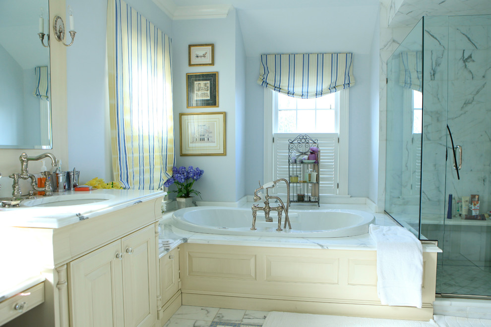 Идея дизайна: главная ванная комната среднего размера в стиле неоклассика (современная классика) с фасадами с декоративным кантом, желтыми фасадами, накладной ванной, душем в нише, серой плиткой, белой плиткой, мраморной плиткой, синими стенами, мраморным полом, врезной раковиной, мраморной столешницей, белым полом и душем с распашными дверями