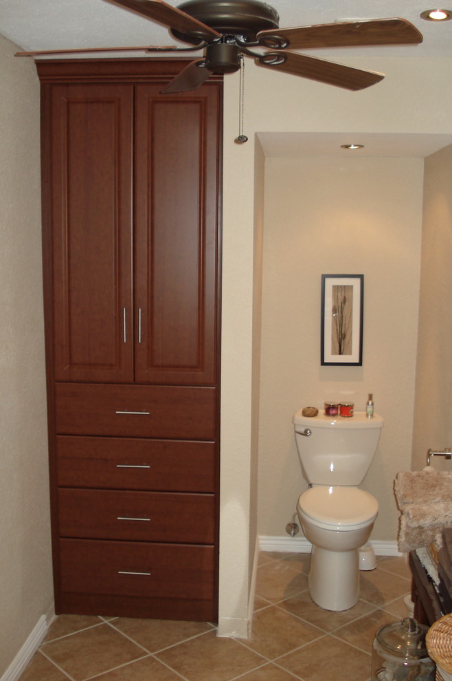 Klassisk inredning av ett mellanstort badrum med dusch, med luckor med upphöjd panel, skåp i mörkt trä, en toalettstol med separat cisternkåpa, beige väggar, klinkergolv i keramik och beiget golv