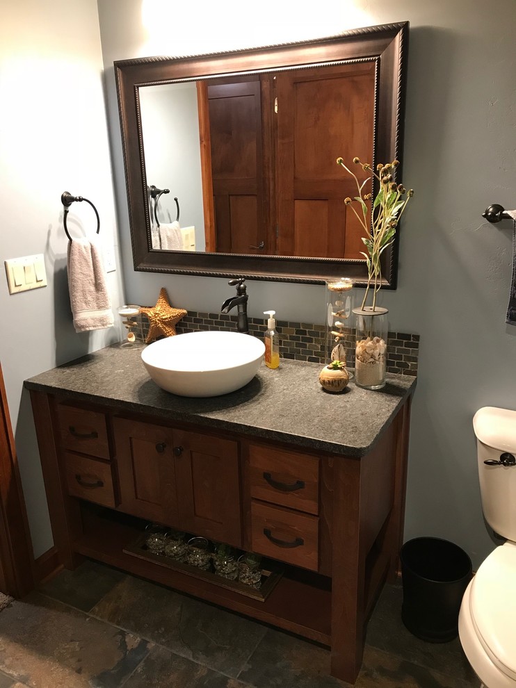 Small transitional 3/4 alcove shower photo in Other with shaker cabinets, medium tone wood cabinets, a two-piece toilet, blue walls, a vessel sink, granite countertops, a hinged shower door and gray countertops