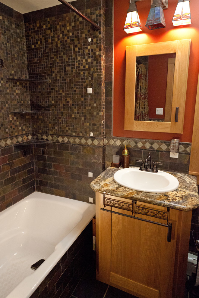 Immagine di una stanza da bagno stile americano con lavabo da incasso, ante in stile shaker, ante in legno scuro, top in granito, vasca da incasso, vasca/doccia e piastrelle multicolore