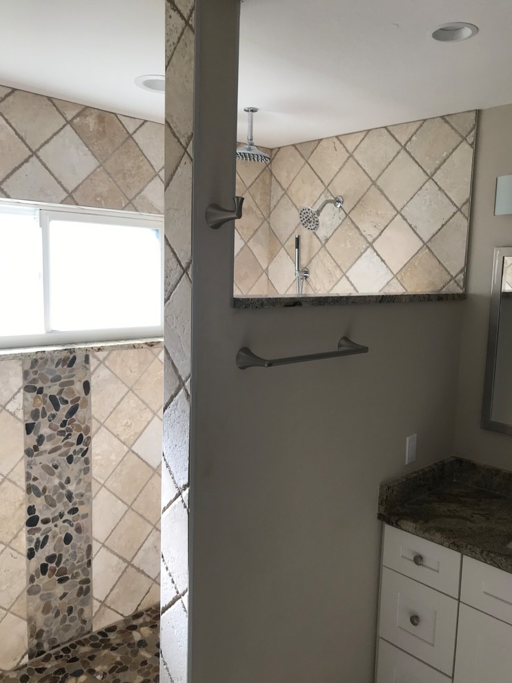 Medium sized traditional ensuite bathroom in Miami with recessed-panel cabinets, white cabinets, a walk-in shower, a two-piece toilet, beige tiles, travertine tiles, beige walls, pebble tile flooring, a submerged sink, granite worktops, an open shower and brown worktops.