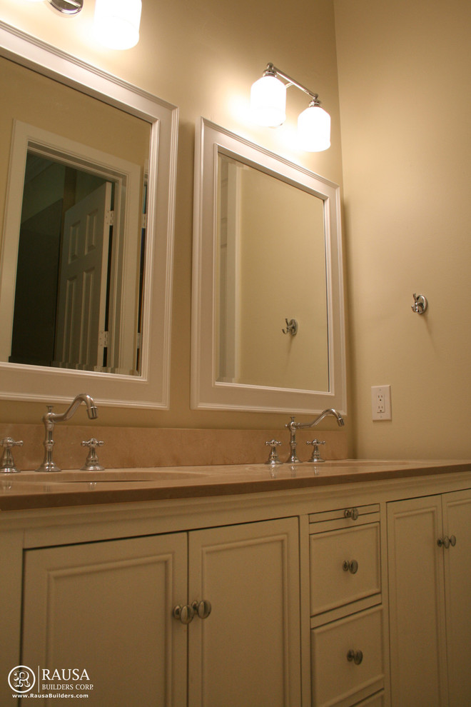 Modern inredning av ett badrum, med ett undermonterad handfat, luckor med upphöjd panel, vita skåp och bänkskiva i kvartsit